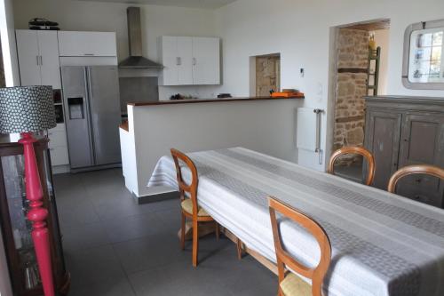 - une cuisine avec une table, des chaises et un comptoir dans l'établissement Maison de village spacieuse et confortable, à Le Gué-de-Velluire