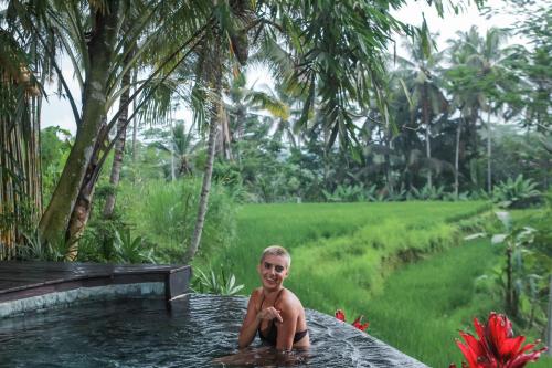 a young boy sitting in a hot tub in a garden at Masakali Retreat in Ubud