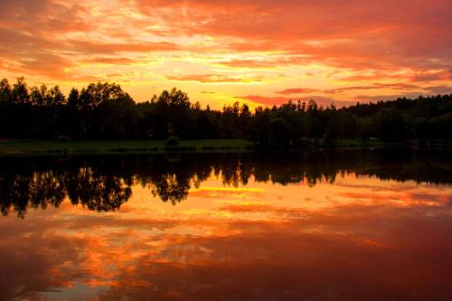 a sunset over a lake with trees in the background at The Hideaway in Želiv