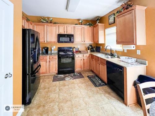 a kitchen with wooden cabinets and black appliances at 3- Bed home with Cali King Bed, 12 mins to DTWN in Atlanta