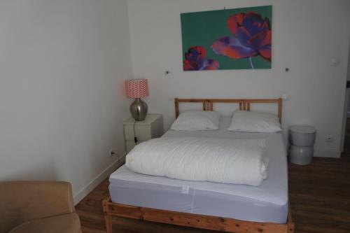 um quarto com uma cama com lençóis brancos e uma cadeira em Maison de village spacieuse et confortable em Le Gué-de-Velluire