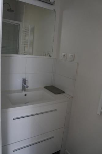 uma casa de banho branca com um lavatório e um espelho em Maison de village spacieuse et confortable em Le Gué-de-Velluire