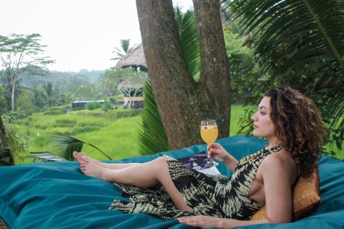 a woman sitting on a blanket with a glass of wine at Masakali Retreat in Ubud