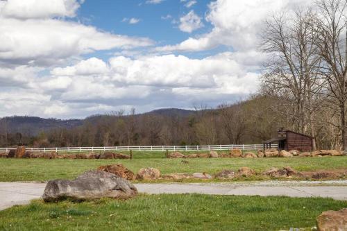 a field with a white fence and a rock at Rustic Modern Getaway - Mtn View - Creek - Hammock - Rest in Sevierville