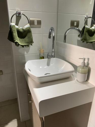 La salle de bains est pourvue d'un lavabo blanc et d'un miroir. dans l'établissement Departamento ideal para viajeros, zona turística, à Santiago