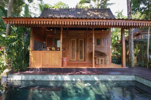 a small house next to a swimming pool at Masakali Retreat in Ubud