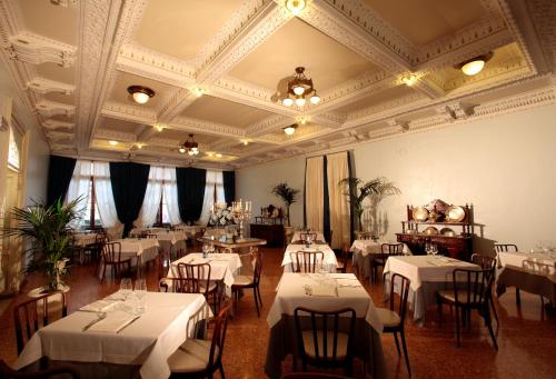 une salle à manger avec des tables et des chaises blanches et un plafond dans l'établissement Hotel Croce Bianca, à Asiago