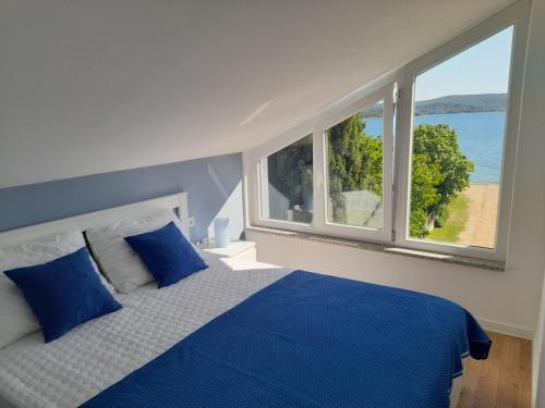 um quarto com uma cama azul e branca e 2 janelas em Apartman prvi red do mora em Sveti Filip i Jakov