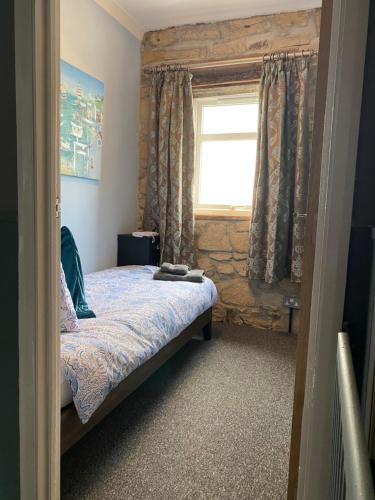 a small bedroom with a bed with a window at The Anchorage - sea views and beach on doorstep in Amble
