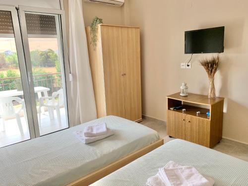 a bedroom with two beds and a tv and a balcony at Lovely apartment by the sea 2 ….. in Epanomi