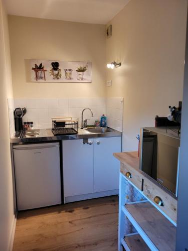 eine kleine Küche mit weißen Schränken und einem Waschbecken in der Unterkunft Studio récent résidence Charles Quint in Gray