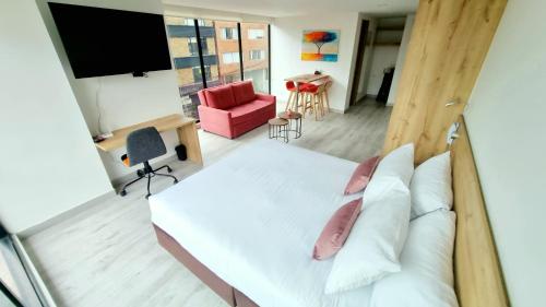a bedroom with a white bed and a red chair at Toscana LOFT - Apartasuites in Bogotá