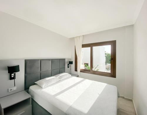 a white bedroom with a bed and a window at Turgutreis Apart Otel in Bodrum City