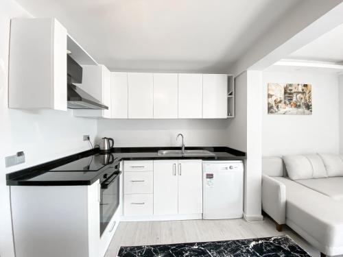 cocina con armarios blancos, fregadero y sofá en Turgutreis Apart Otel, en Bodrum City
