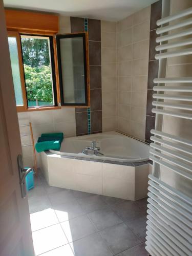 une salle de bain avec une baignoire, un lavabo et une fenêtre dans l'établissement la champagnolaise, à Champagnole