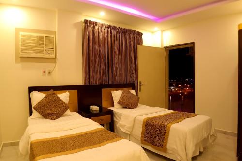 a hotel room with two beds and a window at شقق أمواج للشقق المخدومه in Al Jubail