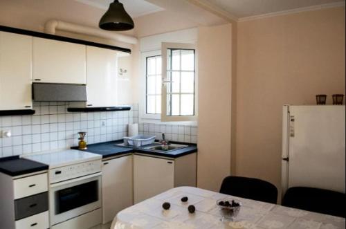 a kitchen with a table and a white refrigerator at Villa Mastiha , Komi Beach in Kómi