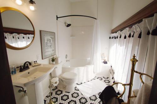 a white bathroom with a tub and a sink at Louisville Bourbon Inn in Louisville