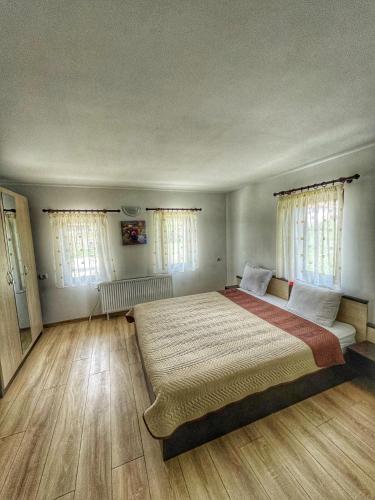 a bedroom with a large bed with wooden floors and windows at Старият Дюкянь in Elena