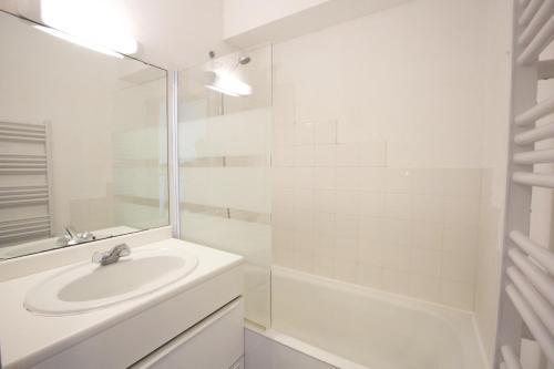 une salle de bain blanche avec un lavabo et une douche dans l'établissement Hossegor - Vue Océan - Plage - Couple - Famille, à Soorts-Hossegor