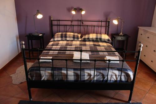 a black bed with a plaid blanket and pillows at Bed and breakfast Agrumi in terrazza in Aragona