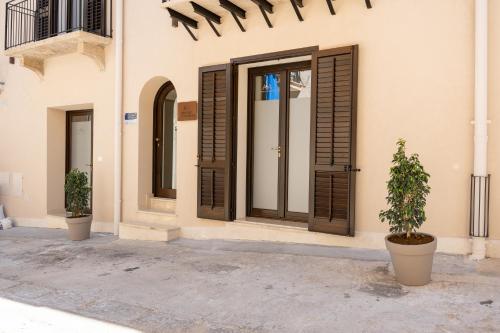 a facade of a building with wooden doors and a plant at ANNICRU' AFFITTACAMERE in Castellammare del Golfo