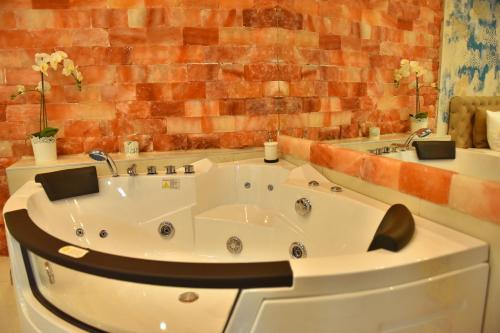 a white bath tub in a bathroom with a brick wall at Design Apartment PREMIUM SPA LUX 4 STAR "DUBAI" Completely PRIVATE Wellness & Spa FREE INCLUDED Sauna & Jacuzzi & Salt Wall & Fire place & 3D Ceilings & Business WiFi & NETFLIX & Keyless code entry & FULL SMART APP & SECURE 2 Parking place in Ćuprija