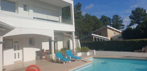 une maison avec une piscine et deux chaises bleues dans l'établissement Maison charmante, à La Teste-de-Buch