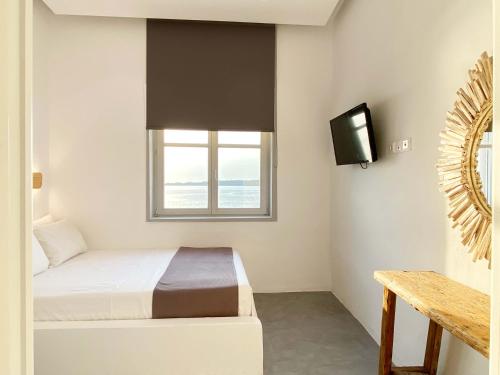 a small bedroom with a bed and a tv at Lyra Seafront Apartment , Paroikia Town Center in Parikia
