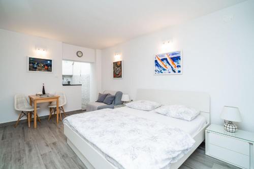 ein weißes Schlafzimmer mit einem Bett und einem Schreibtisch in der Unterkunft Studio Apartment Lapad in Dubrovnik