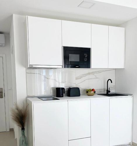 a kitchen with white cabinets and a microwave at Blue View in Lokva Rogoznica