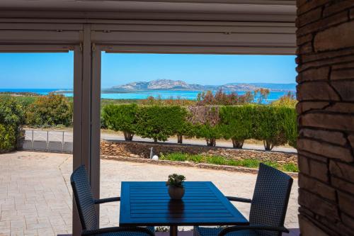 una mesa y sillas en un patio con vistas al océano en Roccabianca Rooms & Studios, en Stintino