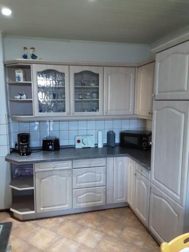 uma cozinha com armários brancos e um frigorífico branco em Haus Helena Dreiländerappartment em Zittau
