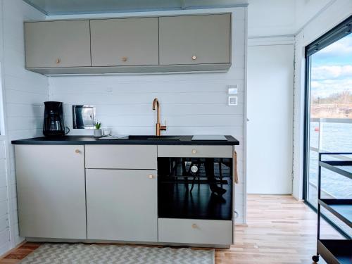 a kitchen with white cabinets and a black counter top at Schwimmendes Haus Johanne auf dem Wasser inkl Boot in Blankaholm in Blankaholm