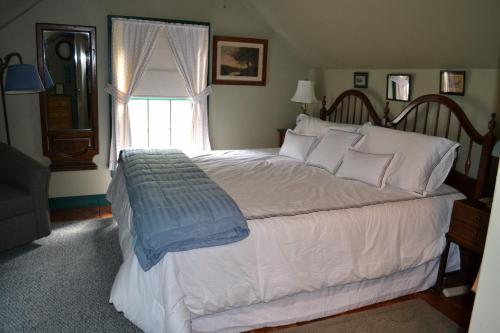 a bedroom with a large white bed with a window at Benjamin Prescott Inn in Jaffrey