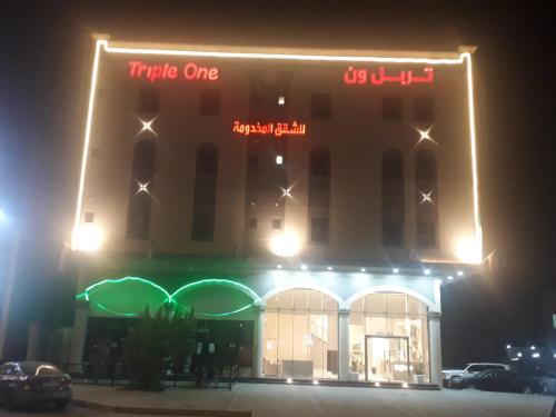 a large building with a neon sign on it at night at تربل وان للشقق المخدومة in Ruqaiqah