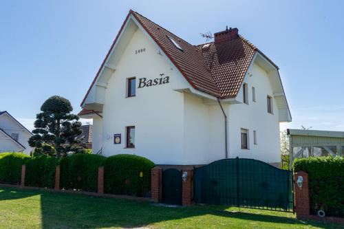 a white house with a sign on the side of it at Pensjonat Basia in Dziwnówek