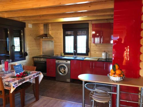 eine Küche mit roten Schränken, einer Spüle und einem Tisch in der Unterkunft Casa de madera el oasis el palomar in Sevilla