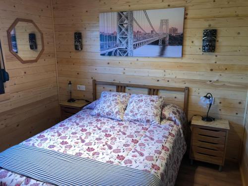 ein Schlafzimmer mit einem Bett und einem Bild einer Brücke in der Unterkunft Casa de madera el oasis el palomar in Sevilla