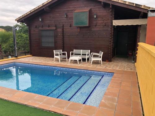a swimming pool with chairs and a house at Casa de madera el oasis el palomar in Seville
