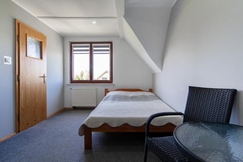 a bedroom with a bed and a table and a window at Pensjonat Basia in Dziwnówek
