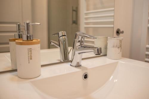 Un lavabo de baño con grifo y espejo. en LeBeauBrun_ HyperCentre_ Duplex, en Amboise
