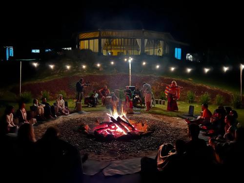 um grupo de pessoas sentadas à volta de uma fogueira à noite em Villarejo Pousada e Experiências em Ibiúna