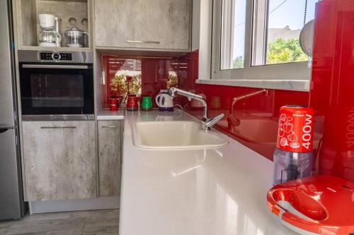 uma cozinha com um lavatório branco e paredes vermelhas em ARTEMISSIA New Well Sided Modish House em Kissamos