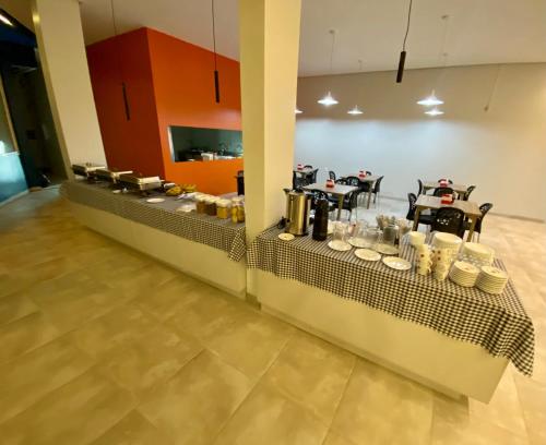 a restaurant with a long counter with tables and chairs at Rota 232 Hotel Caruaru in Caruaru