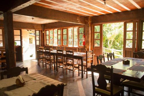 a dining room with tables and chairs and windows at Pousada Cascata in Casimiro de Abreu