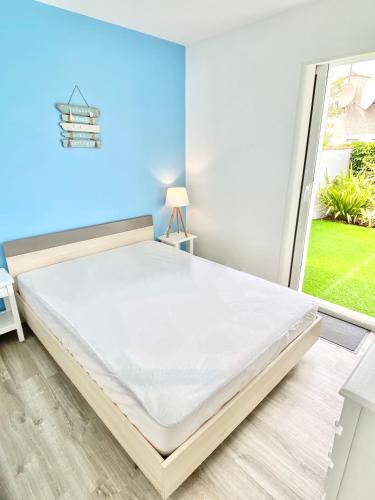 un grand lit dans une chambre avec une fenêtre dans l'établissement ÎLE D OLÉRON Charmante Maison Oléronaise & Piscine chauffée, à Saint-Georges-dʼOléron