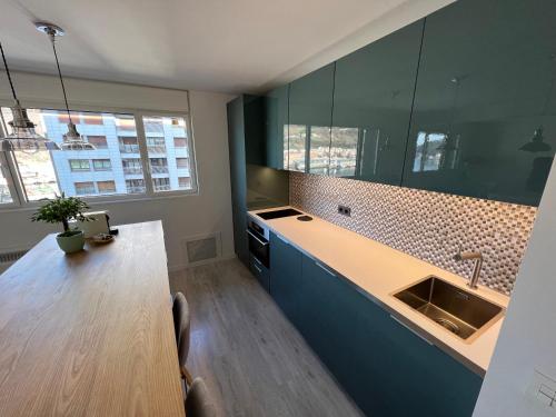 eine Küche mit einem Waschbecken und einem Holztisch in der Unterkunft Apto con vistas a BAHÍA DE PASAJES, a 10 min del centro de San Sebastián in Lezo