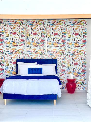 a bedroom with a blue bed with a colorful wallpaper at Moringa Resort - Studio A with Pool open air shower & Bath in Willemstad