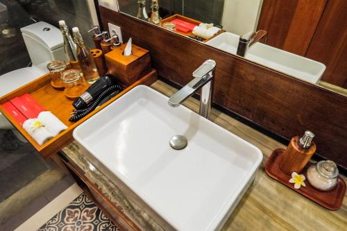 a bathroom with a sink and a toilet and a mirror at Sampatti Villas in Seminyak